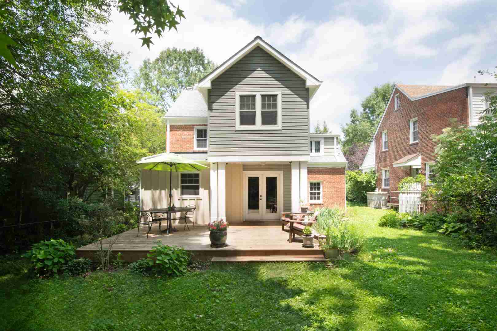 Image of a two-story older home in Southern Maryland with brick and green vinyl siding remodeled by Villa Builders.