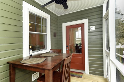 Cozy outdoor seating area with a red door and green siding in a remodeled home by Villa Builders in Annapolis, MD