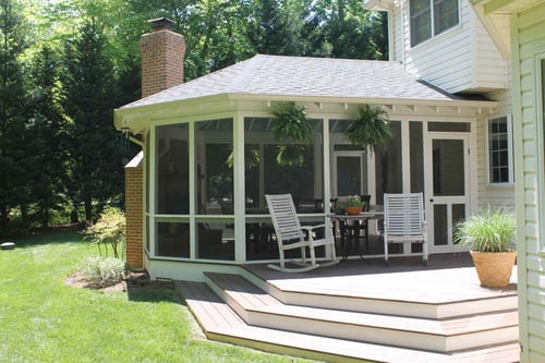 Screened-in porch addition with white trim and cozy seating area by Villa Builders in Annapolis, MD