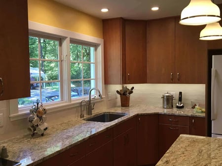 Warm and inviting kitchen with wooden cabinets, granite countertops, and a large window by Villa Builders in Annapolis, Maryland