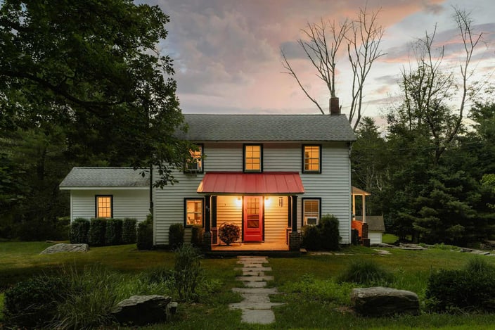 Charming countryside home with a red door and warm evening lighting, captured during a sunset in Southern Maryland