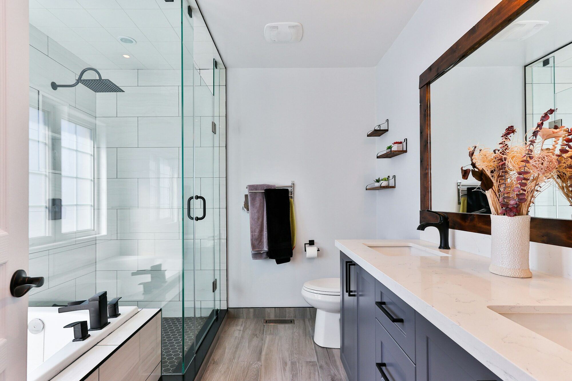 Modern bathroom remodel with a glass-enclosed shower and rustic mirror by Villa Builders in Southern Maryland Modern bathroom remodel with a glass-enclosed shower and rustic mirror by Villa Builders in Southern Maryland