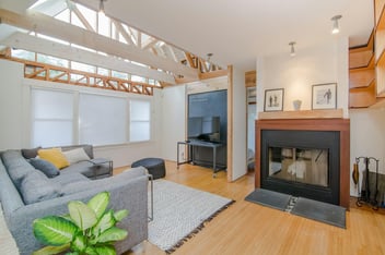 Modern living room with exposed beams and a cozy fireplace, part of a custom renovation by Villa Builders in Southern Maryland