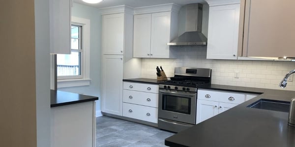 L-shaped kitchen layout in Calvert County, MD with black, laminate countertop, white cabinets, and stainless steel appliances