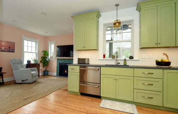 Front view of a remodeled kitchen in a historic bungalow-style home in Southern Maryland with a open layout, granite counters, and pastel green cabinets