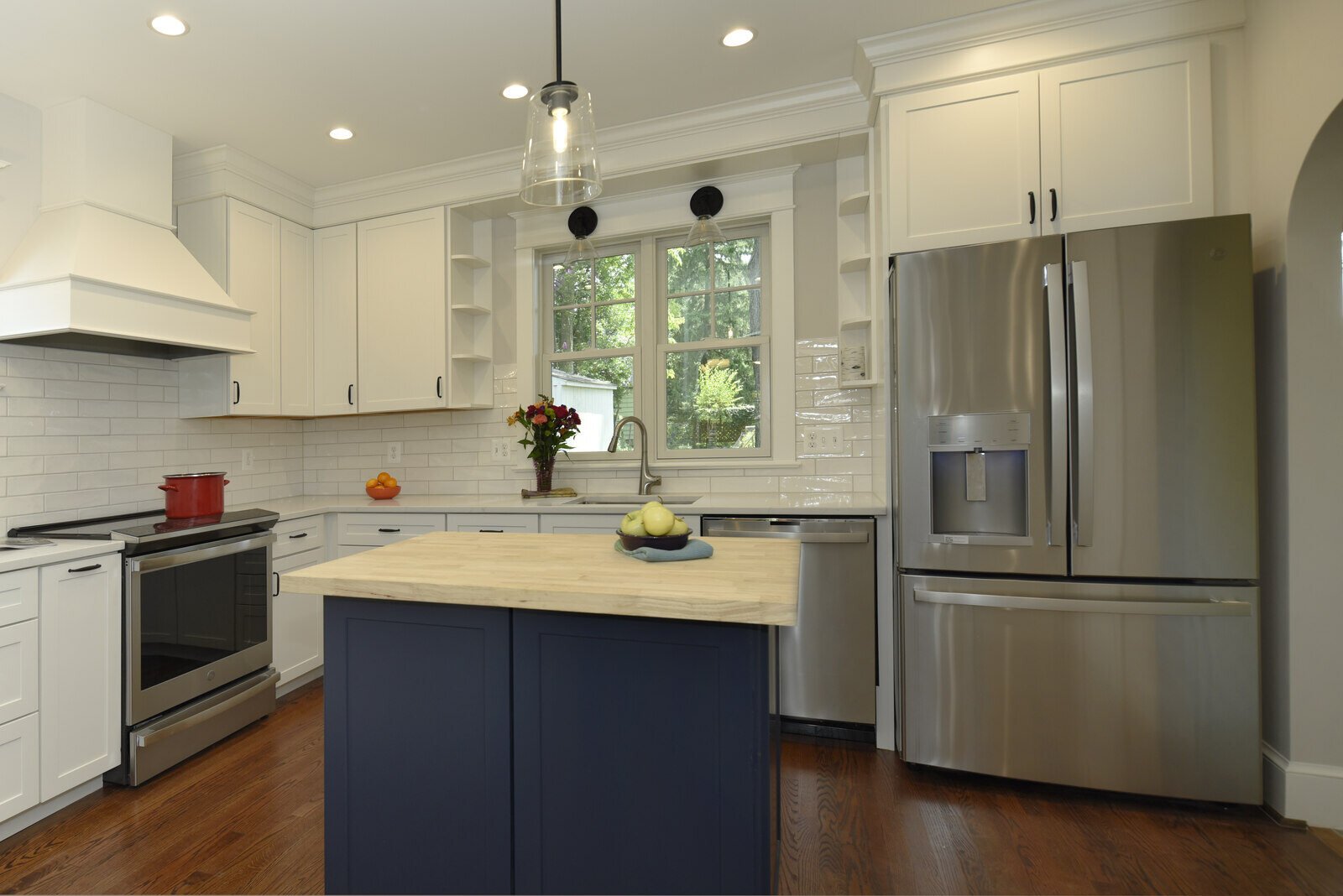 Modern kitchen with a navy center island, white cabinets, and large windows in an Annapolis remodel by Villa Builders