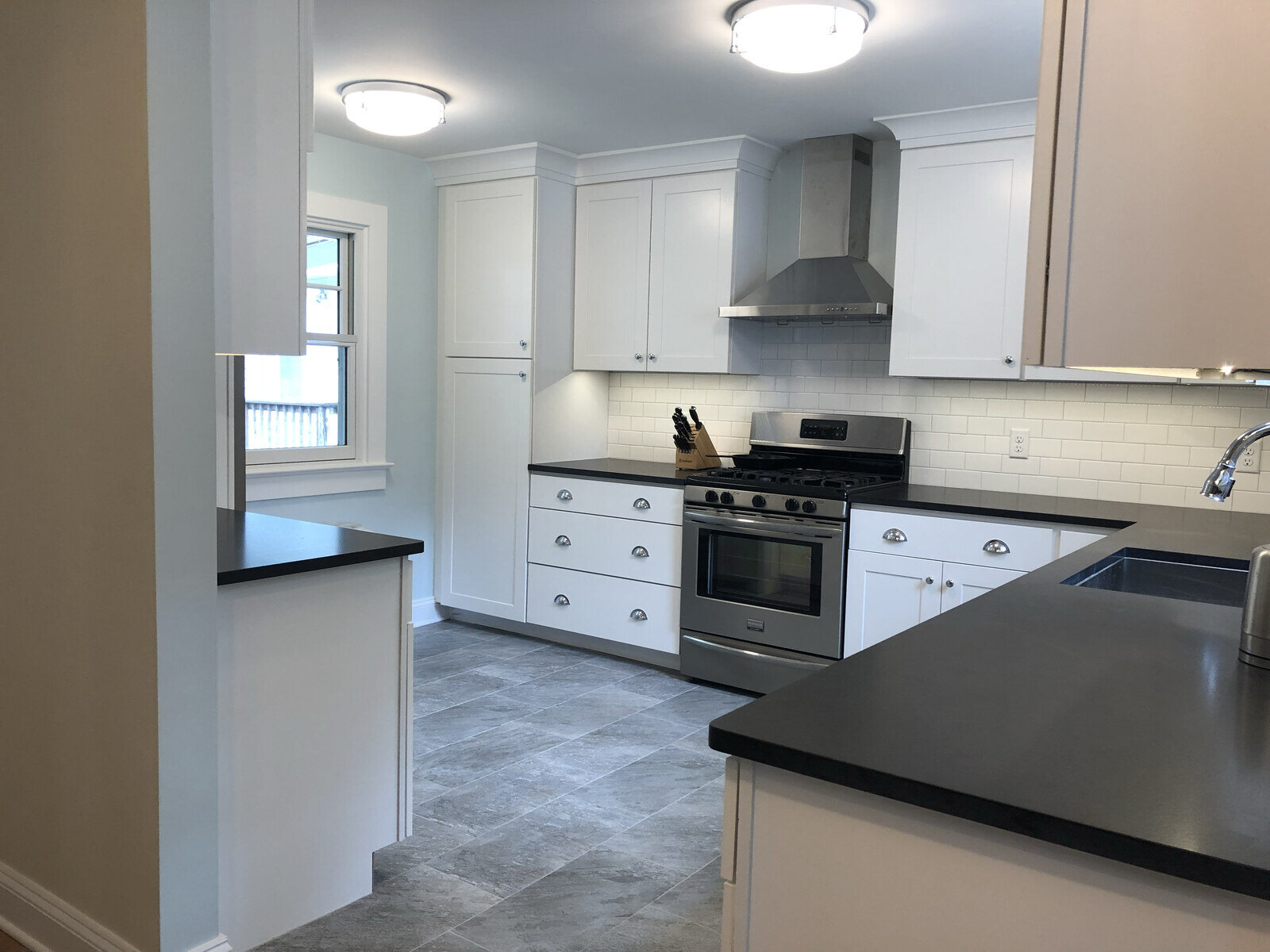 Sleek white kitchen with black countertops and subway tile backsplash, remodeled by Villa Builders in Annapolis, MD