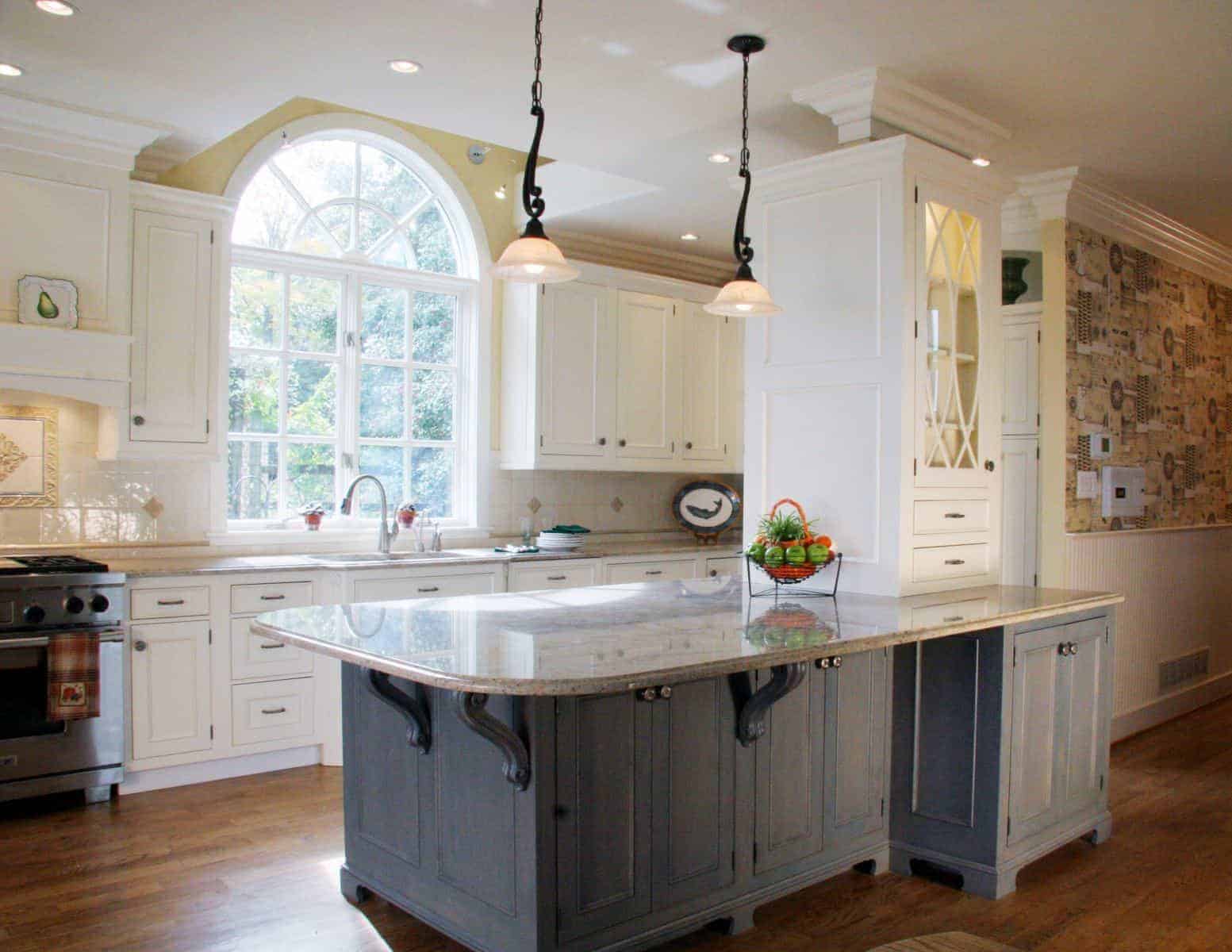 Beautiful kitchen with a large central island, granite countertops, and an arched window by Villa Builders in Annapolis, Maryland