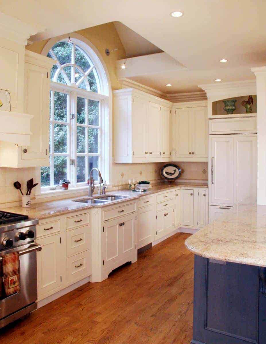 Modern kitchen featuring white cabinetry, a large sink, and a beautiful arched window by Villa Builders in Annapolis, Maryland