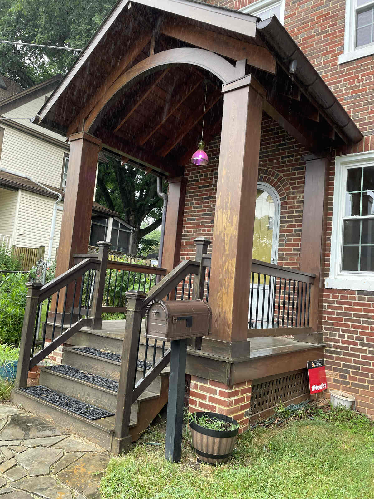 Charming wooden front porch addition with arched roof and brick accents by Villa Builders in Annapolis, MD